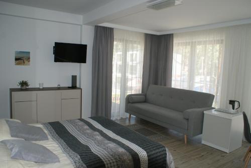 a bedroom with a bed and a couch and a television at Willa Alcala in Pobierowo