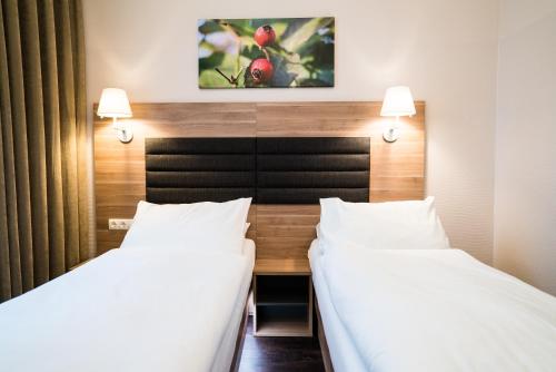 two beds in a hotel room with white sheets at Hotel Marc Aurel - Vienna City Center in Vienna