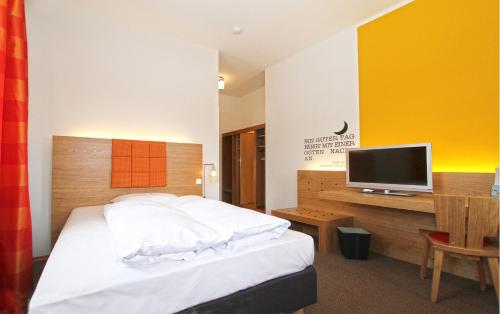 a hotel room with a bed and a tv at Hotel Gut Schwaige in Ebenhausen