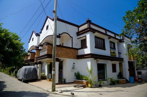duży biały dom z balkonem na ulicy w obiekcie Florabells Iraya Guest House - Batanes w Basco