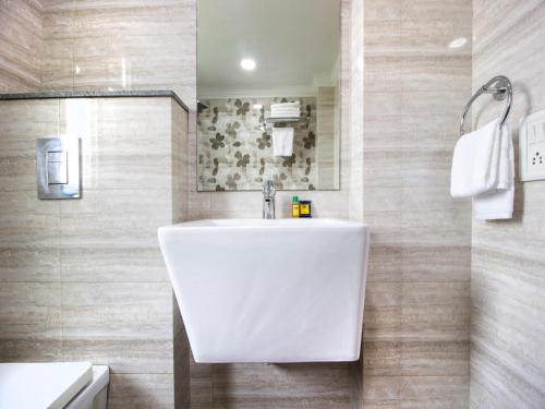 ニューデリーにあるGreen Lotus Residency Dwarkaの木製の壁のバスルーム(白い洗面台付)