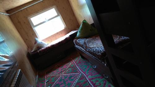 a small room with a couch and a window at Ala-Kul guesthouse in Altyn-Arashan in Karakol