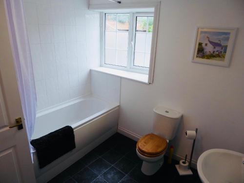 a bathroom with a tub and a toilet and a window at Vermuyden Apartment in Epworth