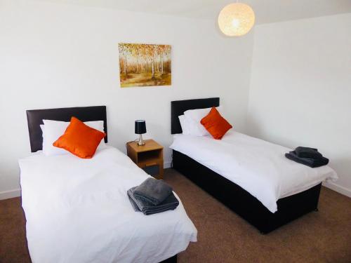 two beds in a room with white and orange pillows at Vermuyden Apartment in Epworth