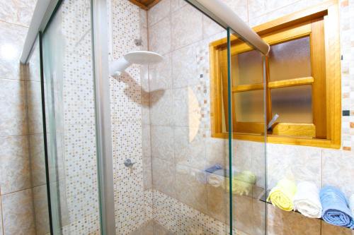 a shower with a glass door in a bathroom at Cantinho dos Coqueiros in Olímpia