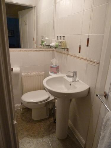 a white bathroom with a toilet and a sink at Burnside Guest House in Ayr