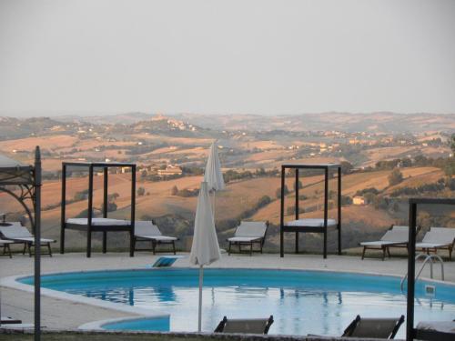 a swimming pool with a umbrella and chairs and a table at Riserva Privata San Settimio in Arcevia