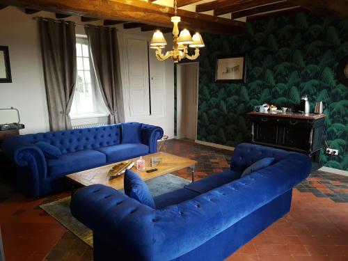 a living room with blue couches and a table at Domaine de la Fauvriere in Sainte-Honorine-de-Ducy