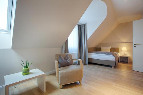Best Western Plus Theodor Storm Hotel في هوسوم: غرفة نوم بسرير وكرسي في العلية