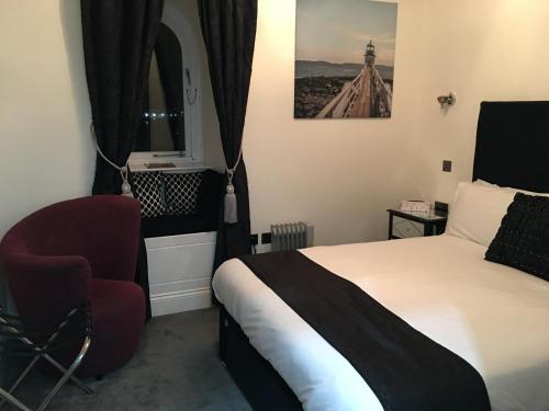 a hotel room with a bed and a chair at The Ship Leopard Hotel - No Children in Portsmouth