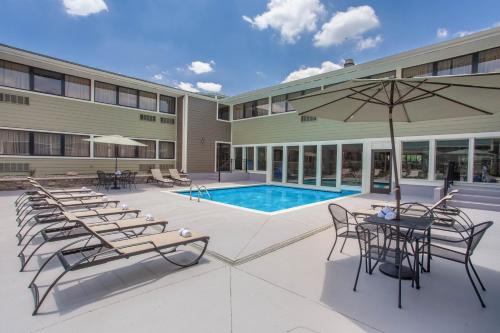a hotel with a pool and chairs and an umbrella at Wyndham Garden Fort Wayne in Fort Wayne