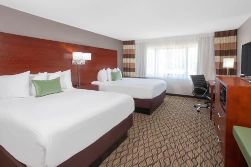 um quarto de hotel com duas camas e uma televisão em Wyndham Garden Fort Wayne em Fort Wayne