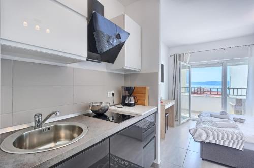 a kitchen with a sink and a view of the ocean at Modern apartments with sea view 150 meters to beach in Kaštela