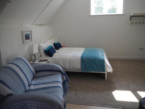 een slaapkamer met een bed, een bank en een stoel bij Hayloft in Pulborough