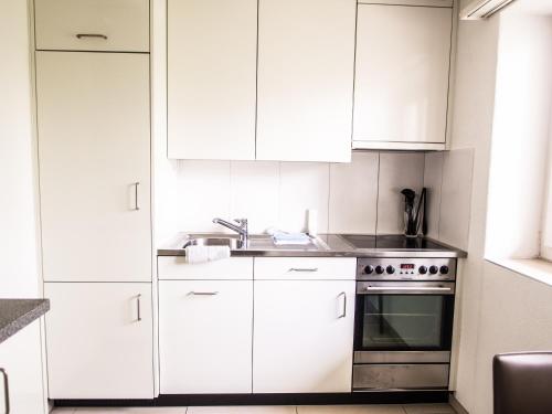a kitchen with white cabinets and a stainless steel oven at CITY STAY - Ringstrasse in Brüttisellen