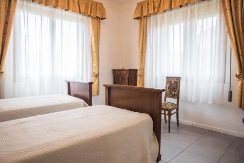 a bedroom with two beds and a chair and windows at Venetian Mood: Secret Garden in Venice