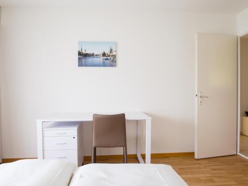 a bedroom with two beds and a desk and a chair at CITY STAY - Ringstrasse in Brüttisellen