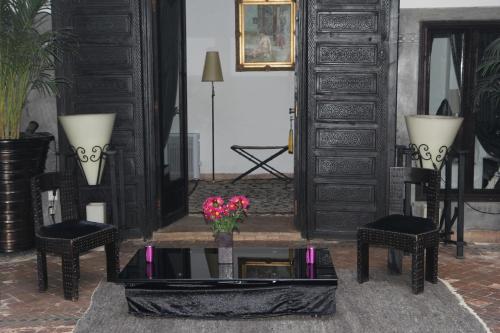 a living room with a table and two chairs and a mirror at Riad Terra Bahia in Marrakech