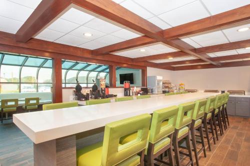 a cafeteria with a bar with green chairs at Wyndham Garden Fort Wayne in Fort Wayne
