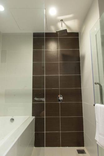 a bathroom with a shower with brown tile at Encorp Marina Suites By Iconic Bliss in Nusajaya