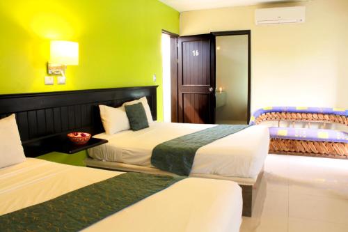 two beds in a hotel room with green walls at Hotel Nautilus in Playa del Carmen