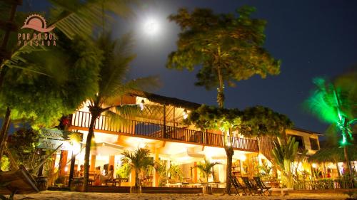 a building with palm trees in front of it at Pousada Por do Sol in Jericoacoara