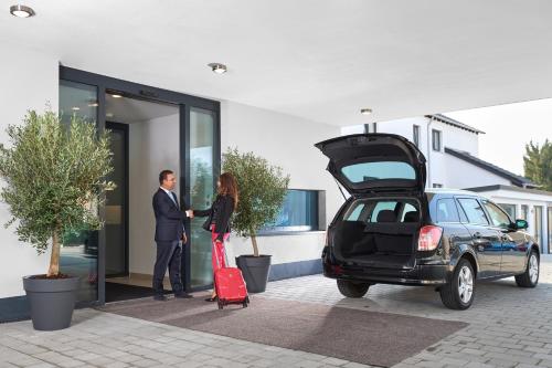 インゴルシュタットにあるHotel New Inのトランクを開けた車の横に立つ男女