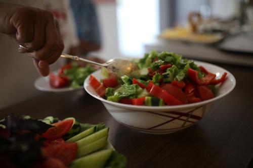 a bowl of salad on a table with a person holding a spoon at Tbilisi View Hotel in Tbilisi City