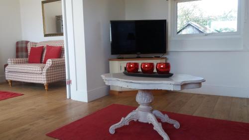 una sala de estar con una mesa con tres manzanas rojas. en Grooms Cottage, en Horncastle