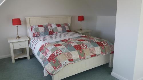 a bedroom with a bed with a quilt and two lamps at Grooms Cottage in Horncastle