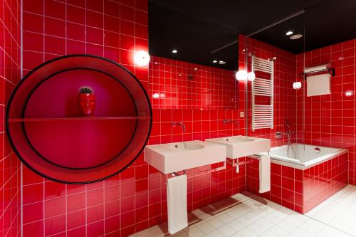 a red bathroom with two sinks and a mirror at Room Mate Bruno, Rotterdam in Rotterdam