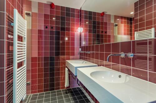 a red tiled bathroom with a sink and a tub at Room Mate Bruno, Rotterdam in Rotterdam
