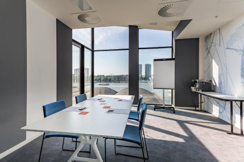 a conference room with a table and chairs and a screen at Room Mate Bruno, Rotterdam in Rotterdam