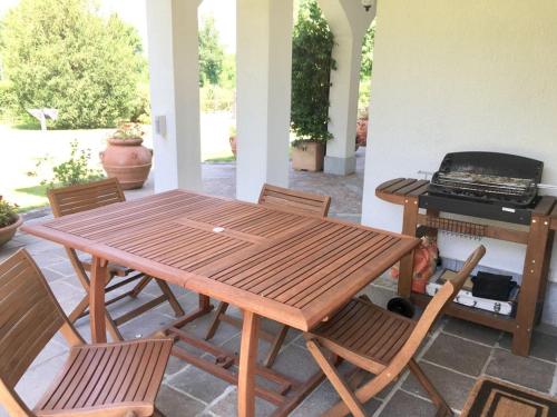 een houten tafel en stoelen op een patio met een grill bij b&b le magnolie in Carimate