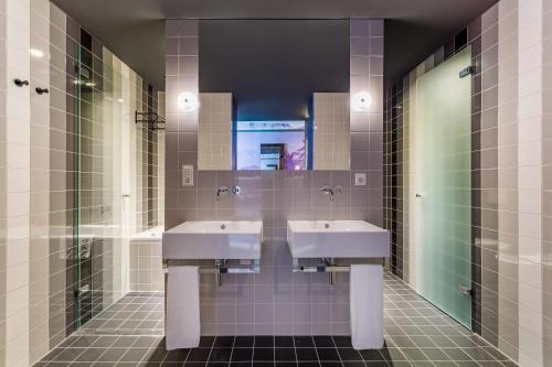 a bathroom with two sinks and a mirror at Room Mate Bruno, Rotterdam in Rotterdam
