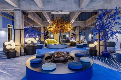 a lobby with a fire pit and blue chairs and trees at Room Mate Bruno in Rotterdam