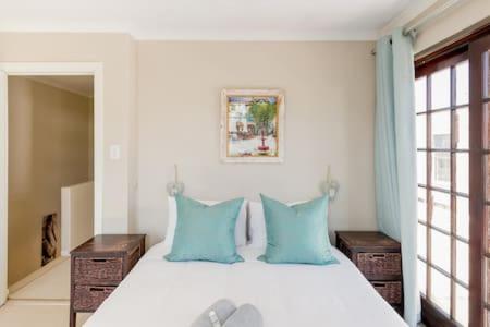 1 dormitorio con 1 cama con almohadas azules en Nansen Place, en Ciudad del Cabo