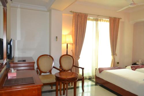 a hotel room with a bed and a desk with chairs at Hotel Nikko Towers in Dar es Salaam