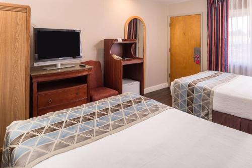 a hotel room with two beds and a flat screen tv at Laurel Inn & Conference Center in Salinas