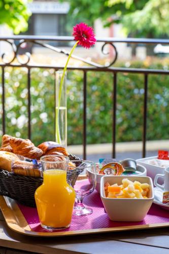 een tafel met een dienblad met ontbijtproducten en een bloem bij Servotel Castagniers in Castagniers