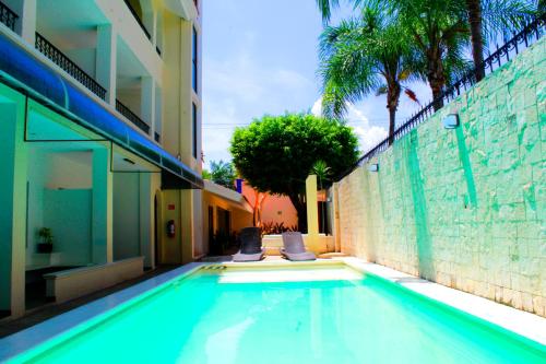 a swimming pool with two chairs next to a building at Hotel Nautilus in Playa del Carmen