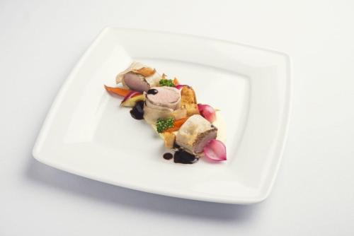 a white plate with food on a white table at Borowinowy Zdrój Hotel Wellness Spa & Conference in Supraśl