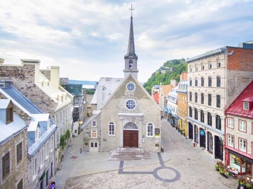 an old building with a church with a steeple at Les Lofts Notre-Dame - Par Les Lofts Vieux-Québec in Quebec City