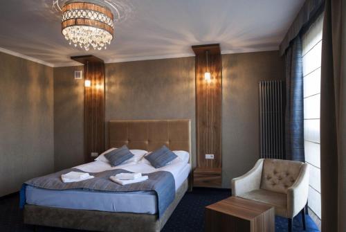 1 dormitorio con 1 cama, 1 silla y 1 lámpara de araña en Borowinowy Zdrój Hotel Wellness Spa & Conference en Supraśl