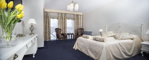 a bedroom with a bed and a table and chairs at Borowinowy Zdrój Hotel Wellness Spa & Conference in Supraśl