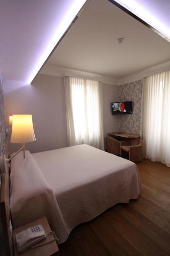 a bedroom with a bed and a lamp and a television at Hotel Metropole Suisse in Como