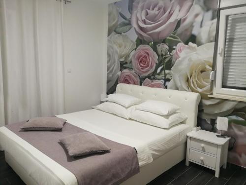 a bedroom with a bed with a flower mural on the wall at Apartman Karma in Bijeljina