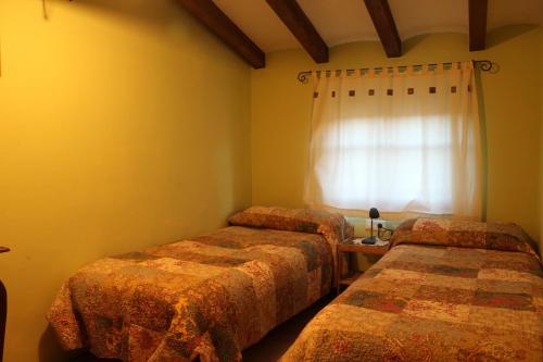 two beds in a room with a window at Ca la Nuri in Senant