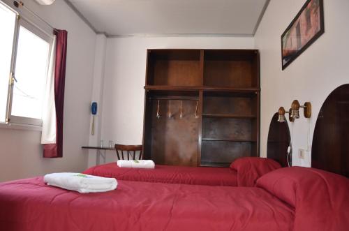 two beds in a room with red sheets at Hotel Romi in Colonia del Sacramento