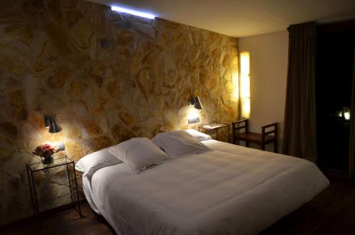 a bedroom with a large bed with a stone wall at Hotel Galena Mas Comangau in Begur